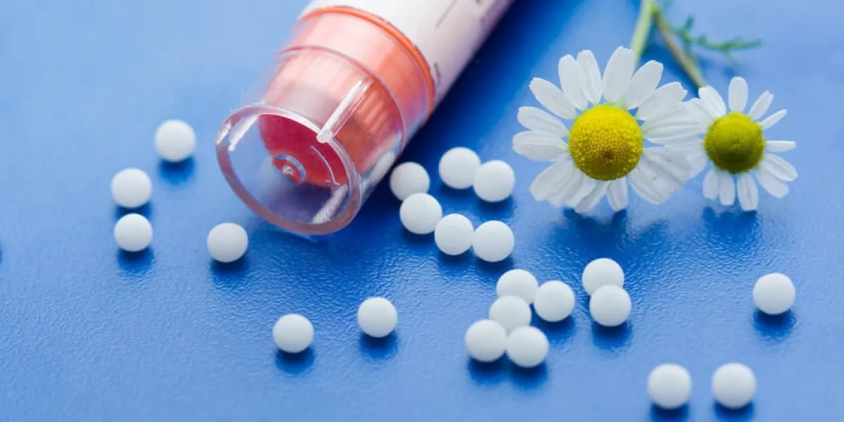 fleur de camomille et médicament homéopathique sur la surface bleue
