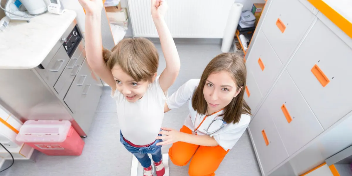 happy kid on a weighing enjoying his growth at doctor visit