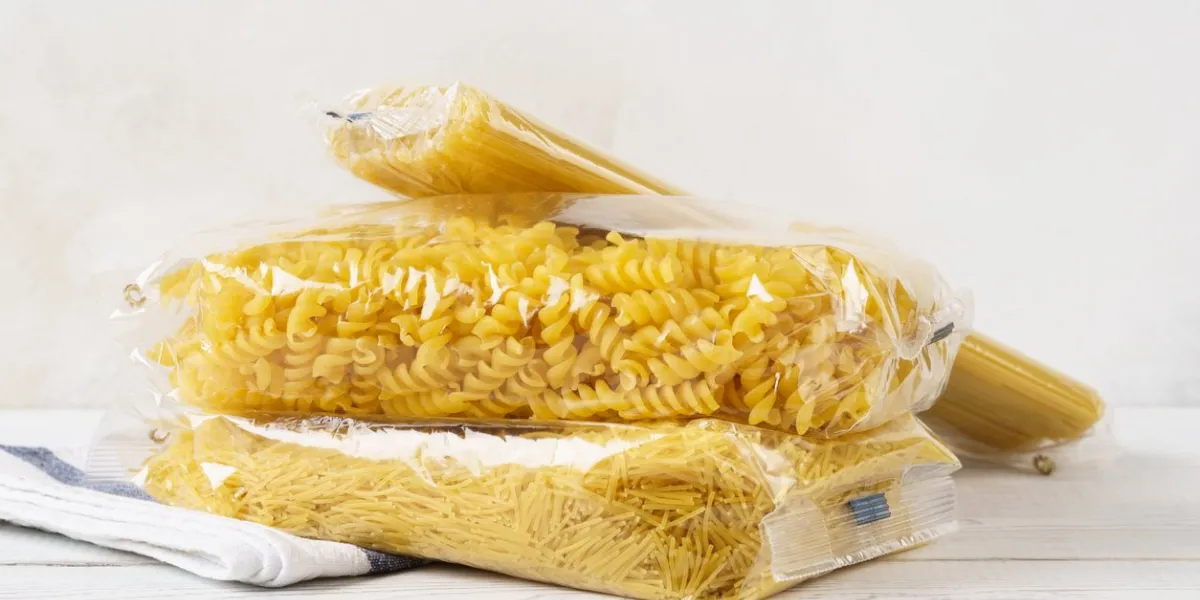various pasta in transparent plastic bags on a kitchen table grocery goods spaghetti, fusilli and vermicelli