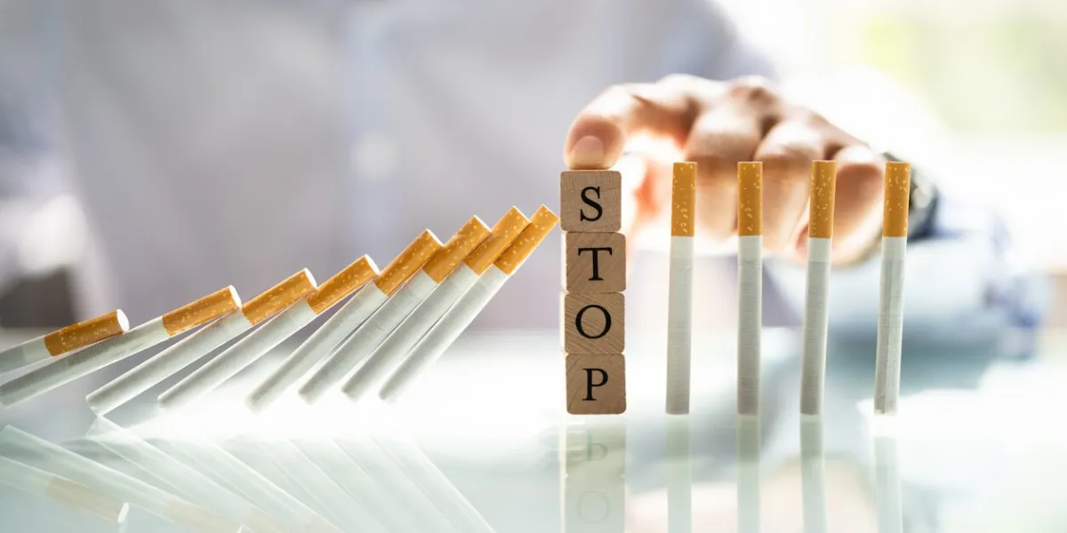 man stopping cigarette from falling on desk with wooden blocks