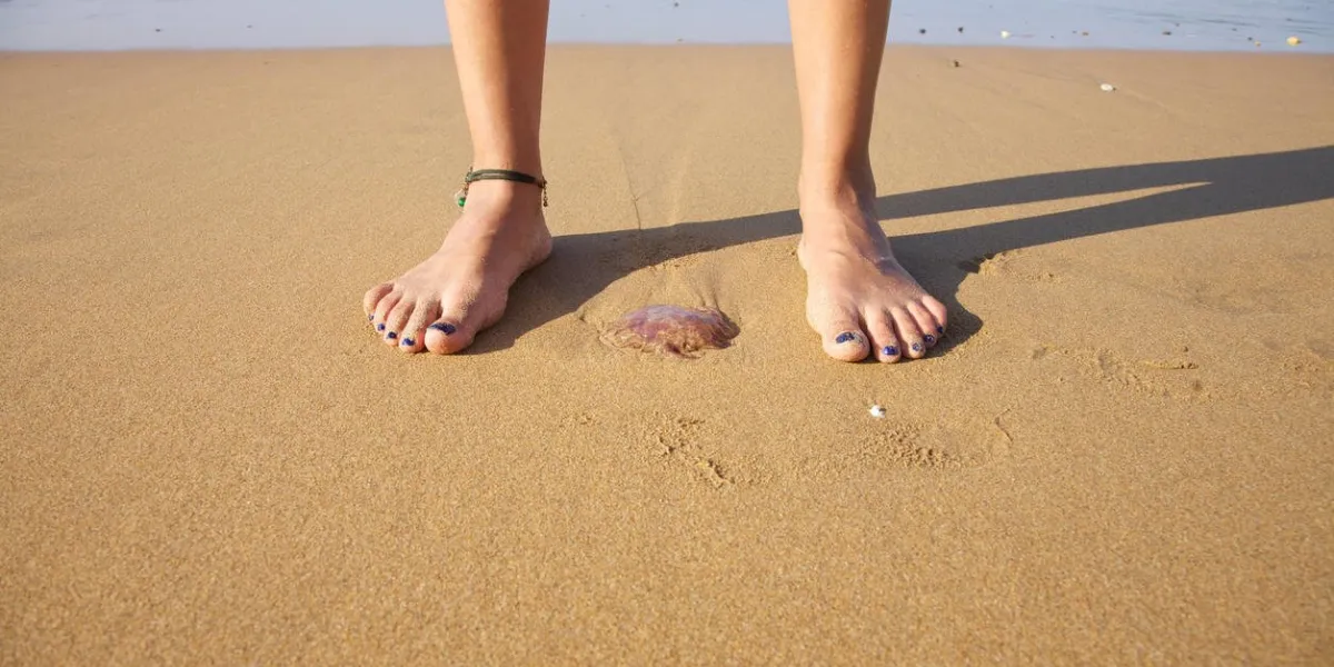 femme pied prêt à pousser une méduse dans une plage