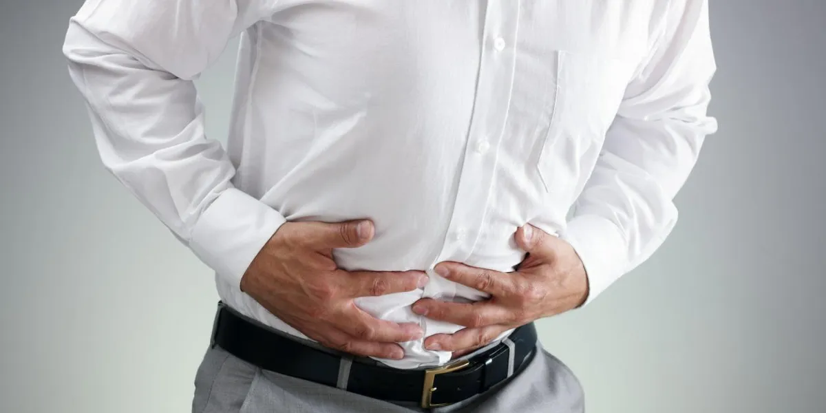 businessman holding his stomach in pain with stomachache or indigestion