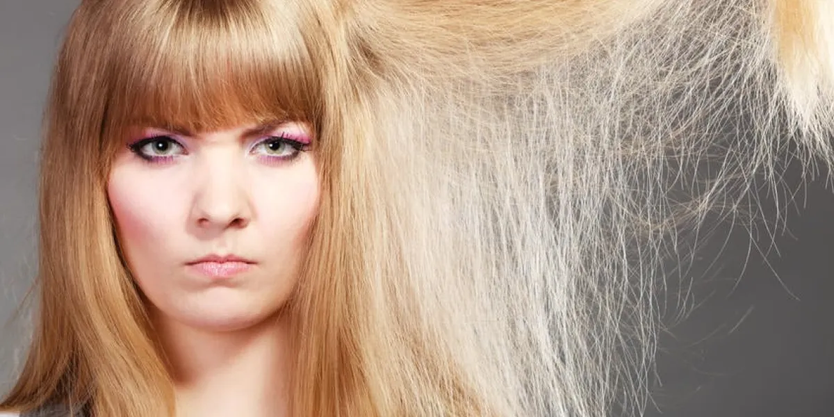 femme blonde avec ses cheveux secs abîmés expression du visage en colère fond gris