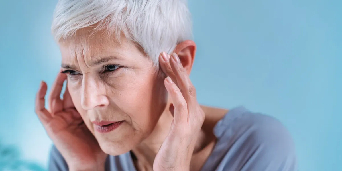 senior woman suffering from tinnitus or ringing in her ears