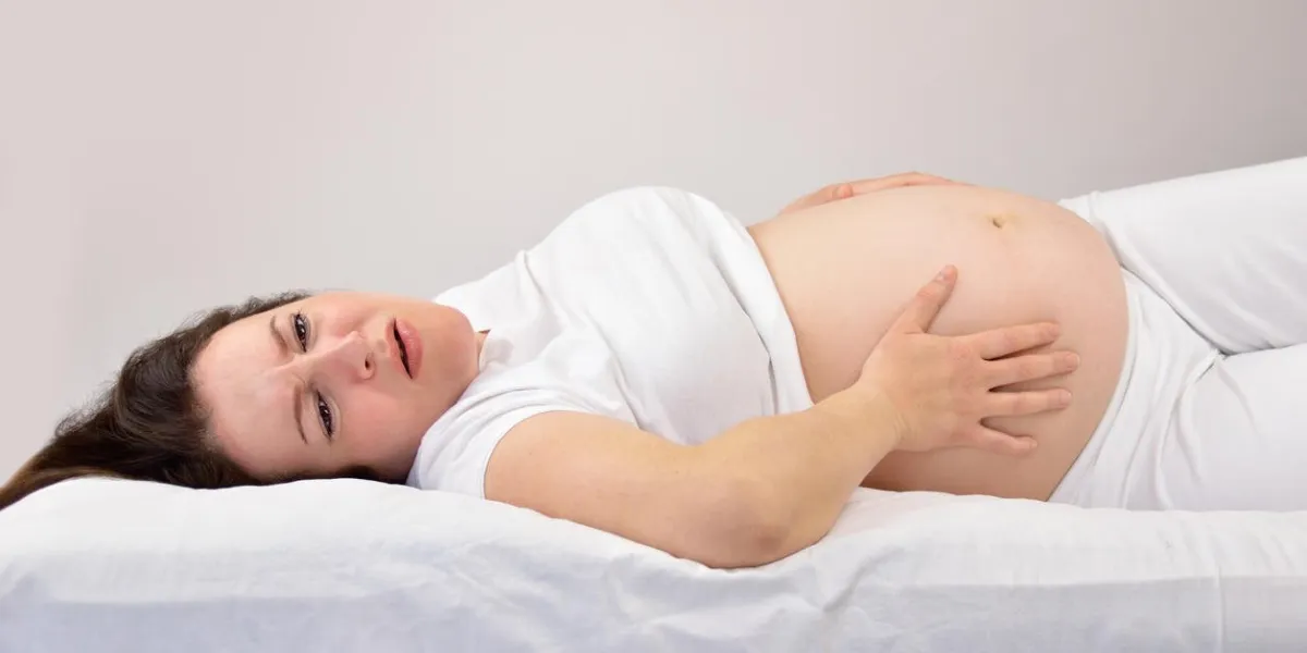 femme enceinte tenant son estomac dans la douleur sur le lit