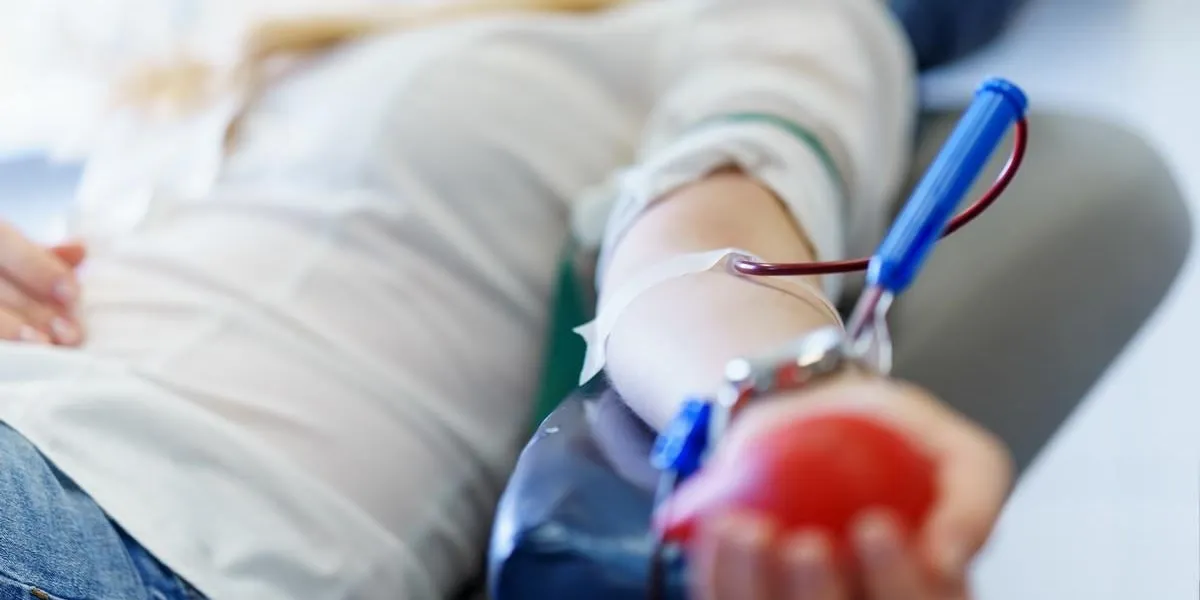 young caucasian woman with toy heart in the hand donates blood for saving lives and medical research in some hospital at day time