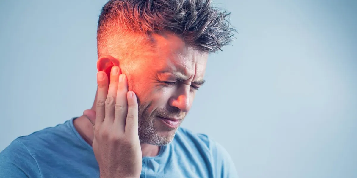 male having ear pain touching his painful head isolated on gray background