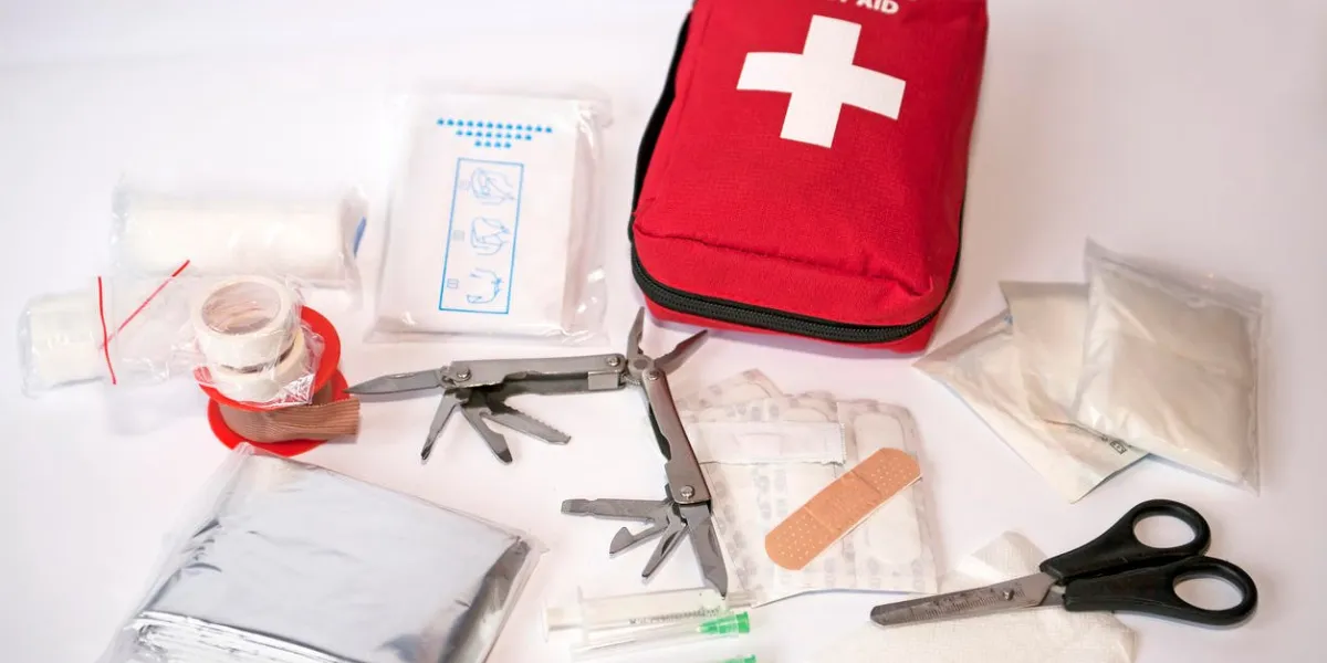 trousse de premiers secours ouverte avec pansements, ciseaux, écharpe triangle, seringue, plâtre, couteau, outils, gaze, etc.