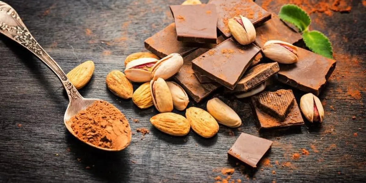 chocolat noir et cacao en cuillère avec mélange de noix sur fond en bois rustique