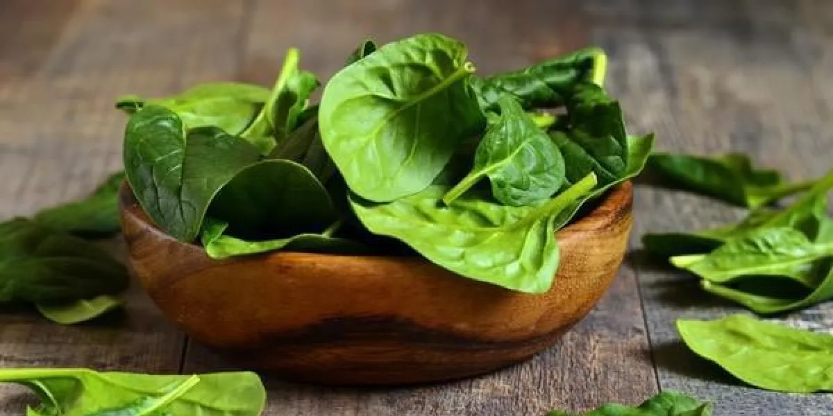 feuilles d'épinard dans un bol en bois sur une table en bois