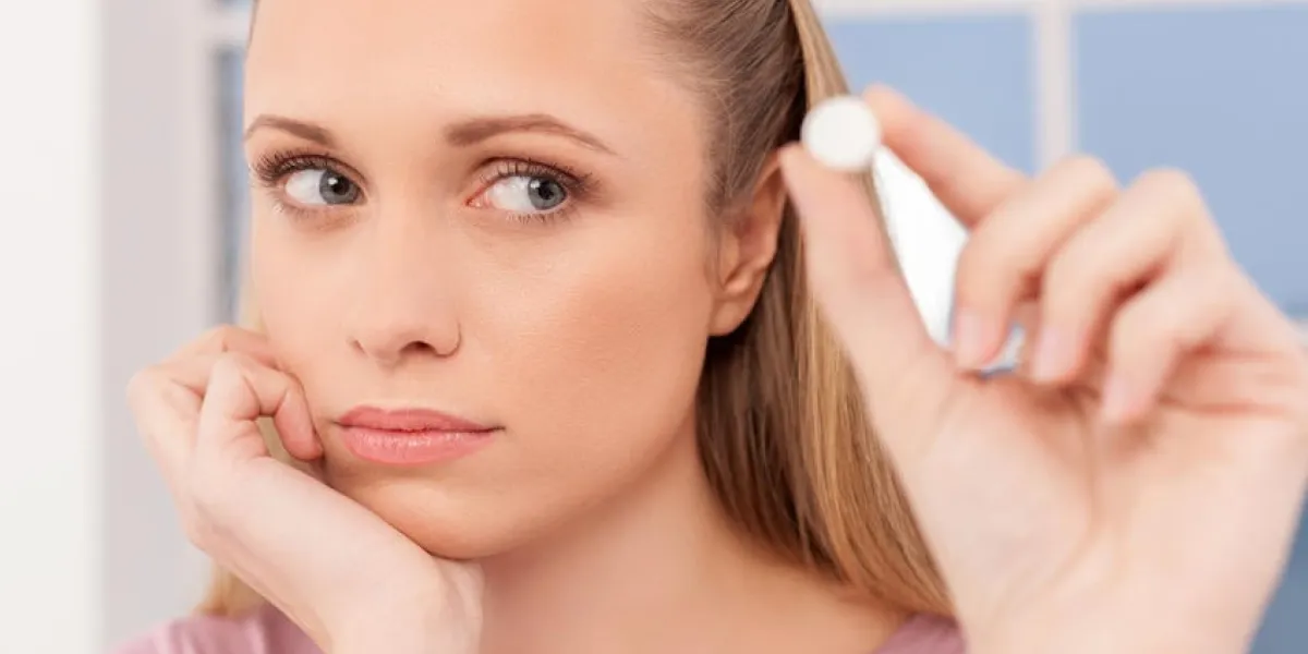 jeune femme déprimée tenant une pilule et la regardant