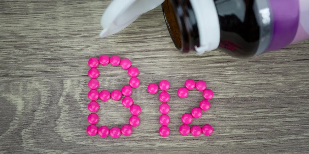 pilules roses formant la forme à l'alphabet b12 sur fond de bois