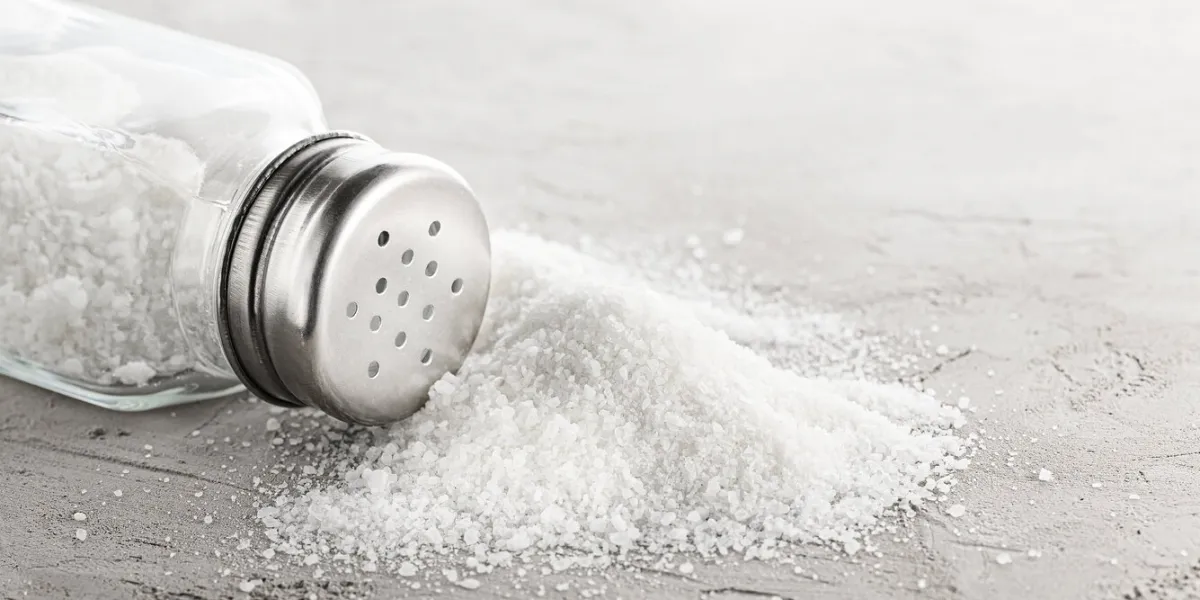 salt shaker and pile of spilled salt on concrete stone