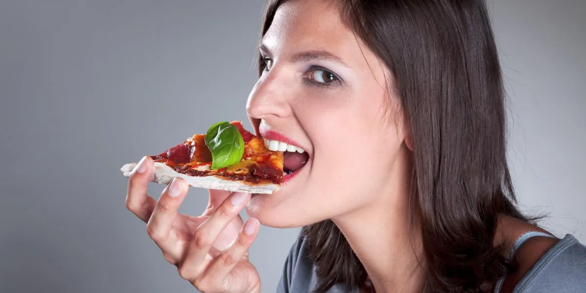 femme mange une pizza au salami