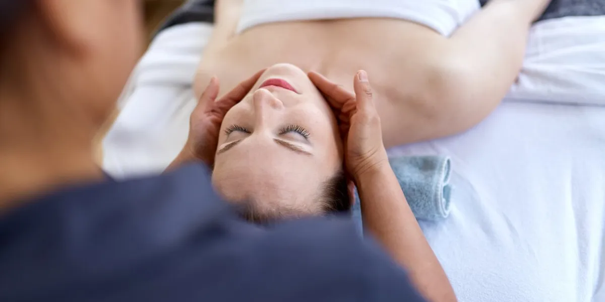 candid image of a blond woman patient during a massage appointment with an asian female physio therapist relaxing in a serene living room