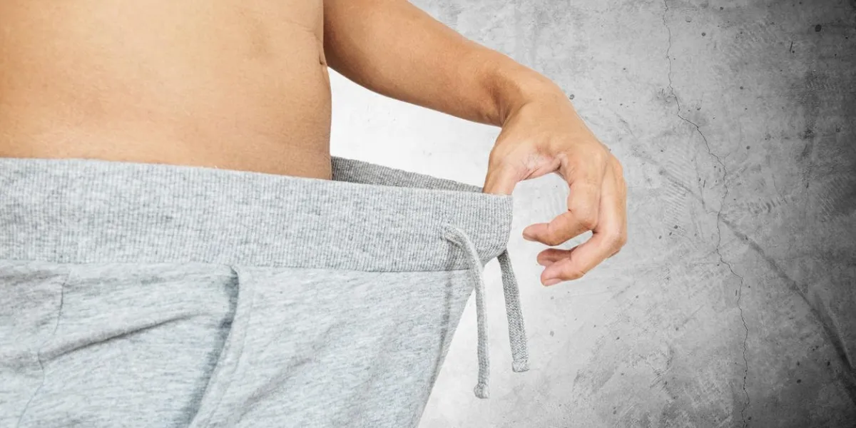 asian guy pulling warm pant, abstract concept, on concrete background