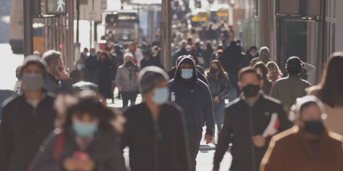 crowd of people walking street wearing masks