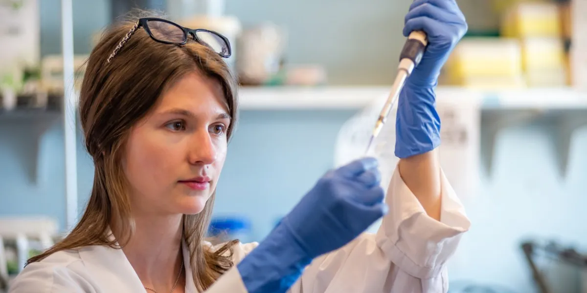 woman researcher in biotechnology laboratory pipetting genetic material
