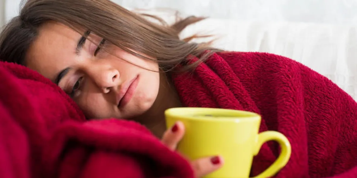 malade jeune fille avec fièvre boire une tasse de thé chaud