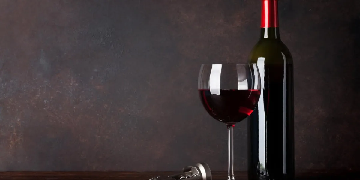 red wine bottle and glass in front of blackboard wall with copy space for your text
