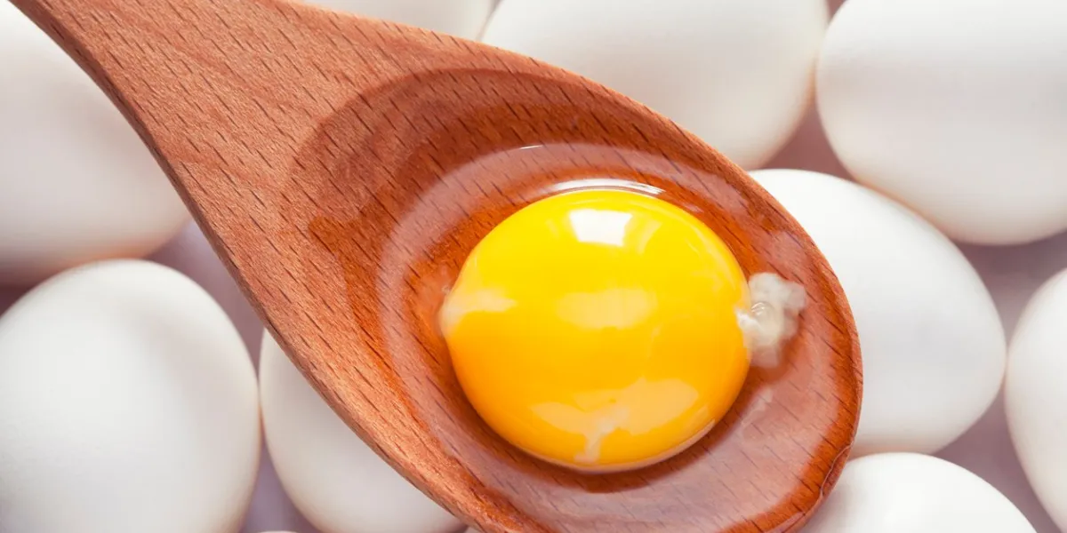 egg yolk in wooden spoon on eggs close up