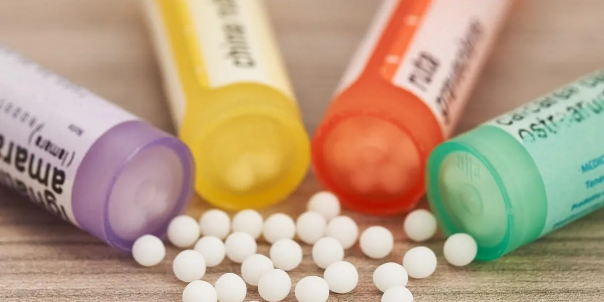 homeopathic globules scattered around with their colored containers in the shape of tube on a wooden table