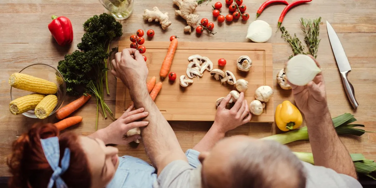 overhead view of mature couple at kitchen table preparing vegan food
