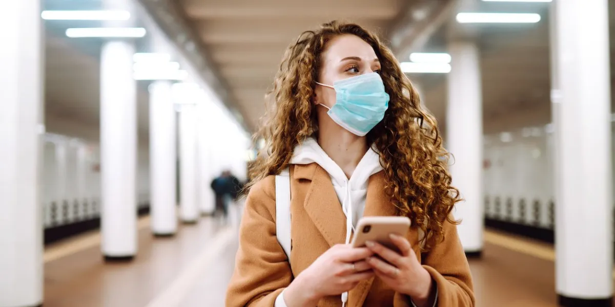 girl in protective sterile medical mask on her face with a phone in a subway car woman using the phone to search for news about coronavirus the concept of preventing the spread of the epidemic