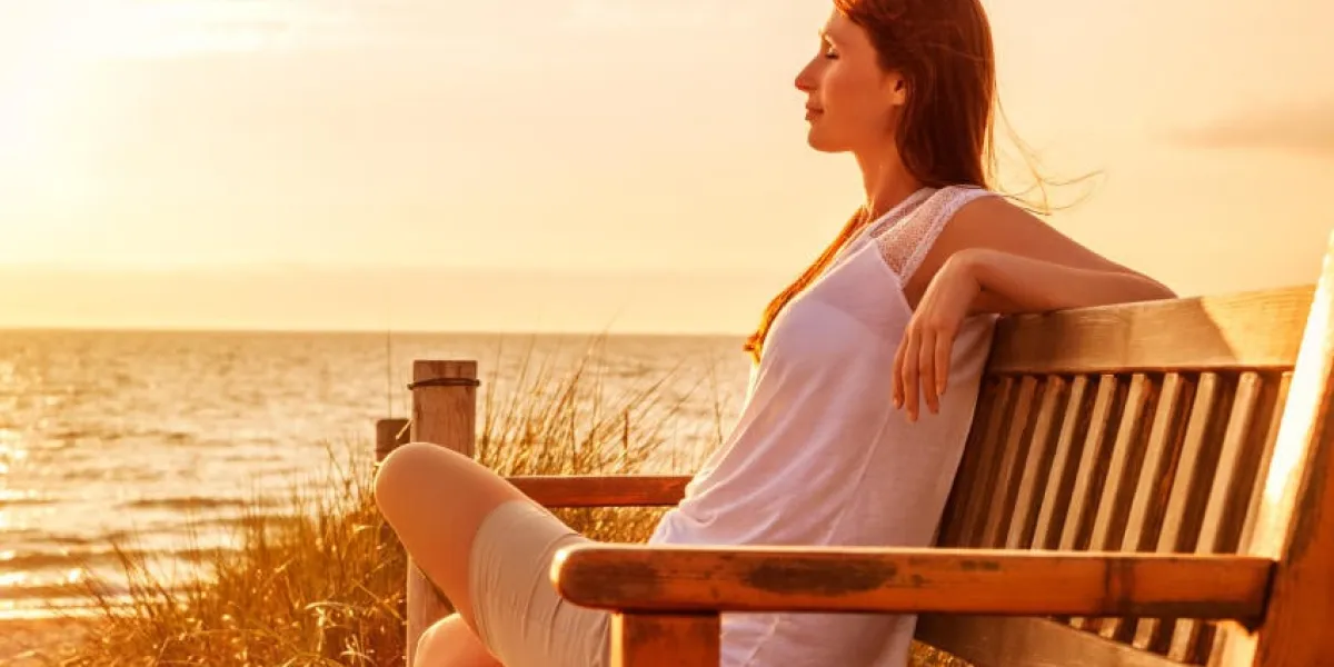 femme relaxante sur la côte du coucher du soleil