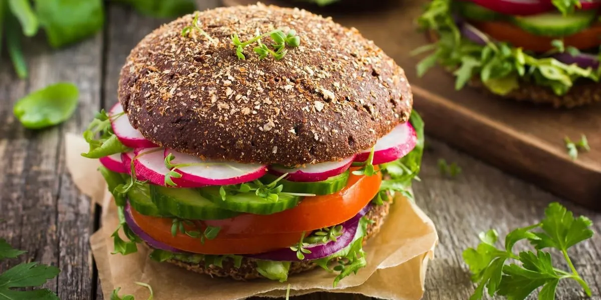hamburger sain de seigle vegan de restauration rapide avec des légumes frais sur le vieux fond en bois