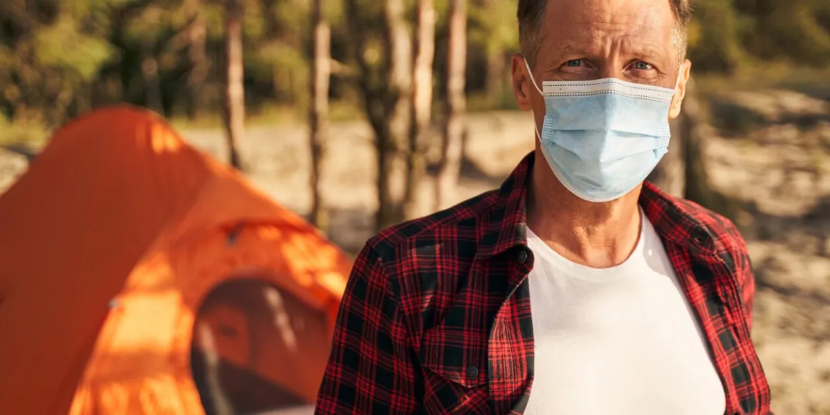 portrait of aged handsome male spending isolation period during pandemic with tent in forest in solitude