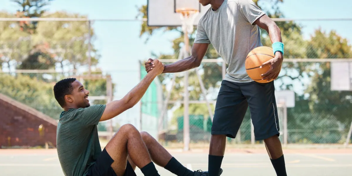 basketball, sports and teamwork, helping hand and support, respect and assistance in competition training games happy basketball player holding hands with friend, trust and kindness on outdoor court