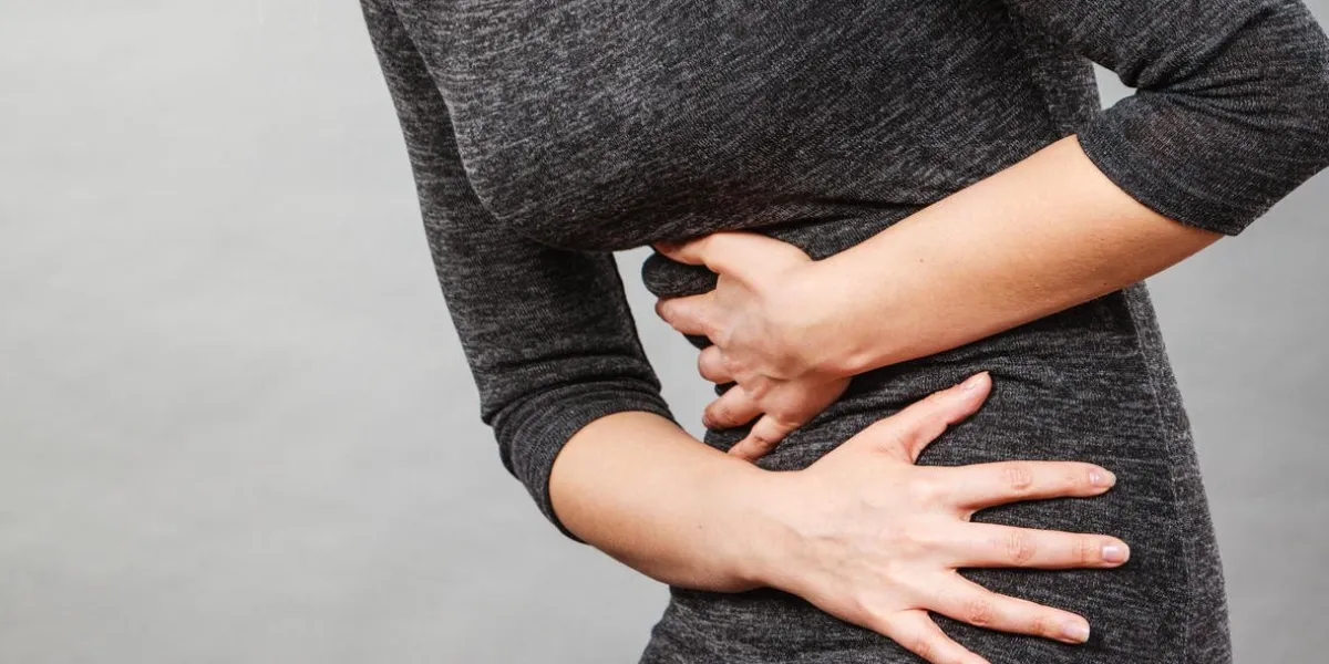 woman having strong stomach ache syndroms of indigestion pregnancy female suffer on belly pain, holds hands on abdomen, part of body on grey
