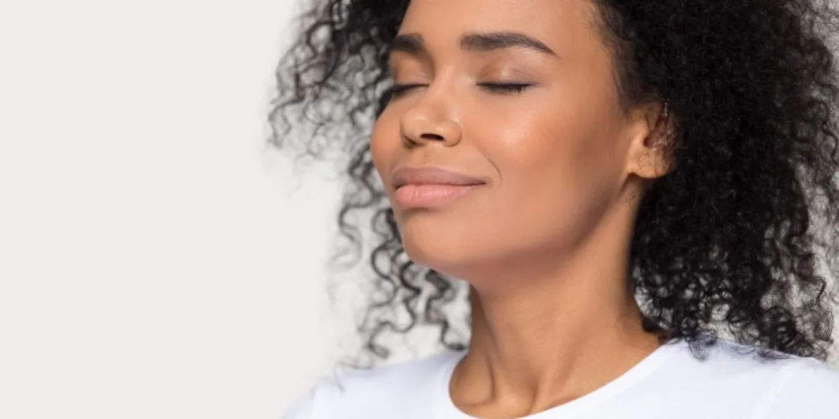 calm peaceful african american woman breathing deep close up, attractive beautiful female with closed eyes enjoying fresh air, meditating, relaxing, no stress concept isolated on studio background