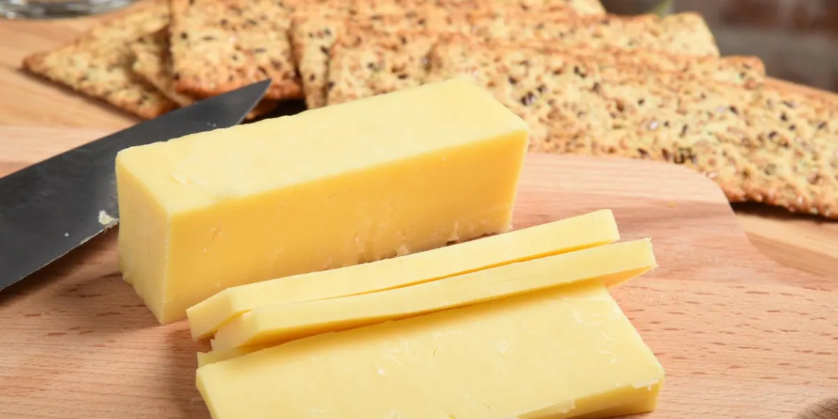 fromage cheddar blanc en tranches sur une planche à découper