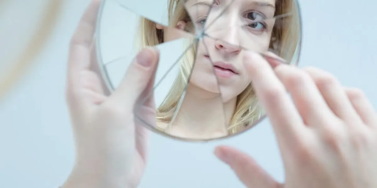 inquiet jolie jeune femme tenant un miroir cassé