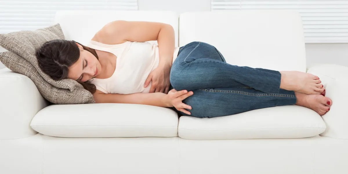 haute vue angle de jeune femme souffrant de maux d'estomac sur le canapé à la maison