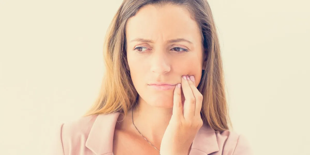 portrait of displeased of young caucasian businesswoman touching her cheek, suffering from toothache