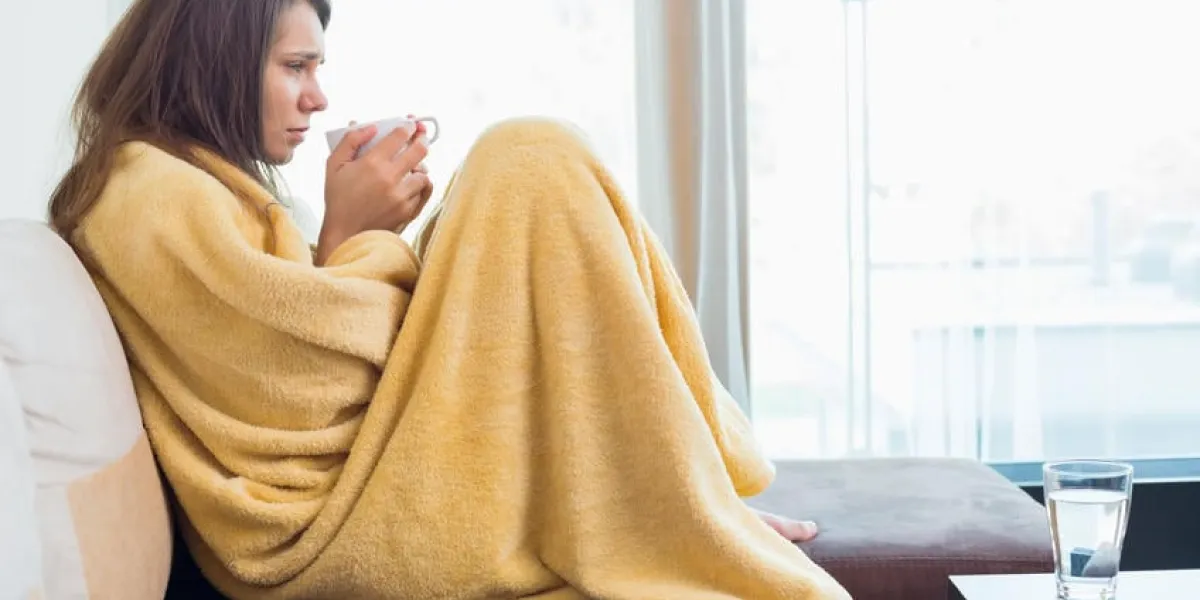 vue de côté de la femme malade ayant du café sur le canapé dans le salon
