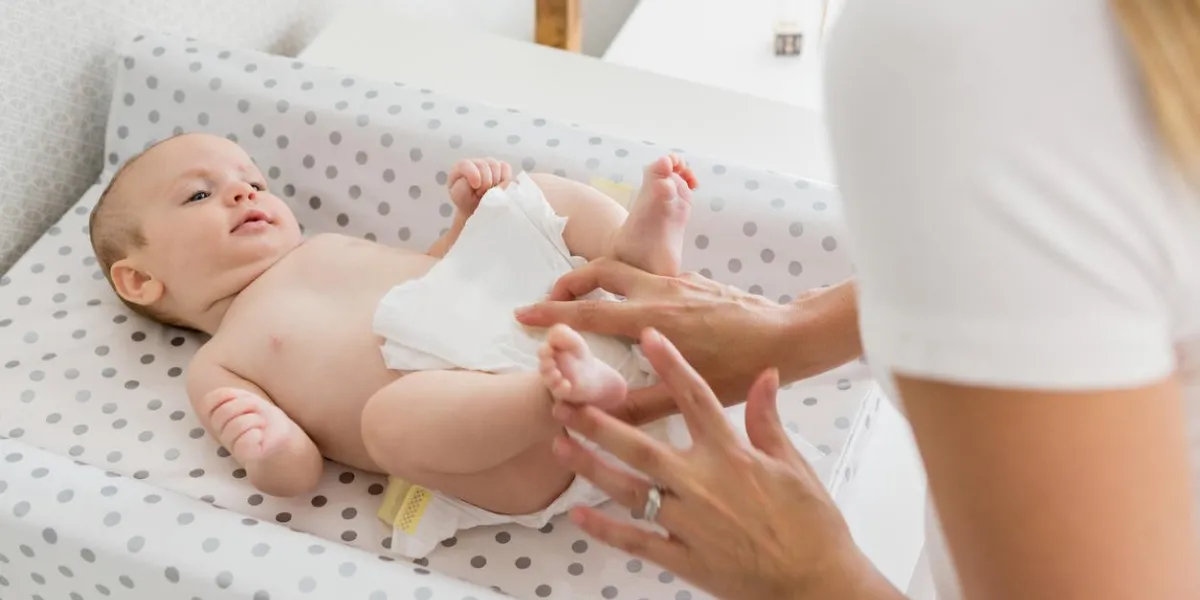 mère changeant la couche de son bébé à la maison