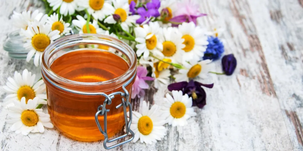pot de miel et de fleurs sauvages sur une table en bois