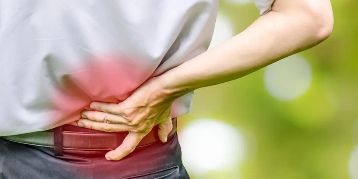 gros plan d'un homme tenant son dos dans la douleur, photo monochrome avec le rouge comme un symbole pour le durcissement