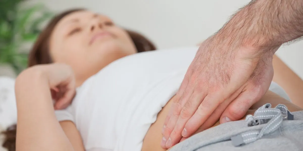 médecin examinant l'estomac de son patient dans une pièce