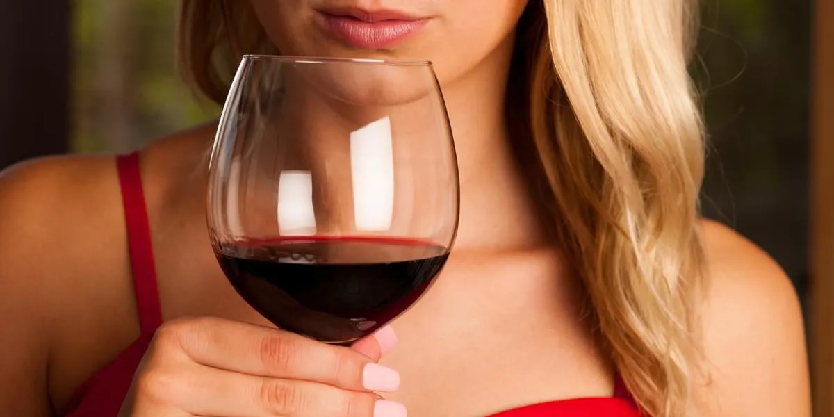 belle femme boit du vin rouge en plein air sur un après-midi d'été chaud