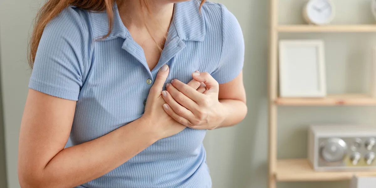 young woman pressing on chest with painful expression severe heartache, having heart attack or painful cramps, heart disease