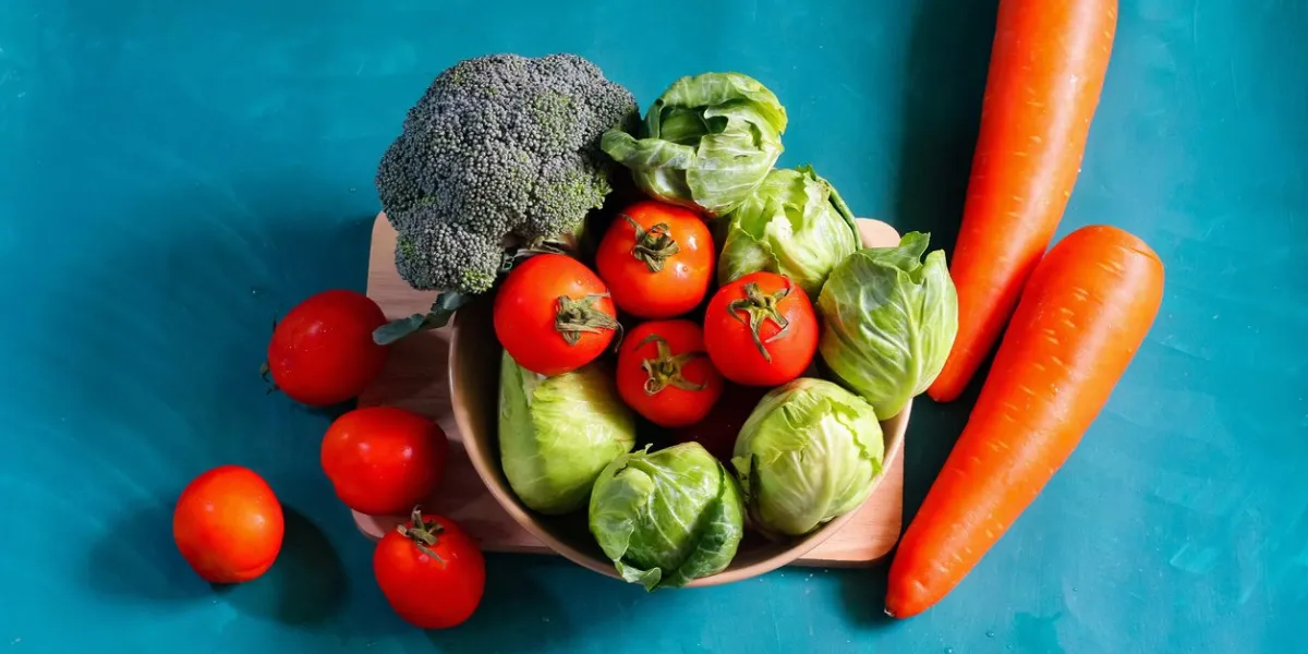 cabbage, lettuce, tomatoes, carrots broccoli fresh vegetable in bowl, healthy diet food, source of vitamin and fiber on ocean green and blue color background with copy space for text or design, vegan food, vegetarian organic vegetables