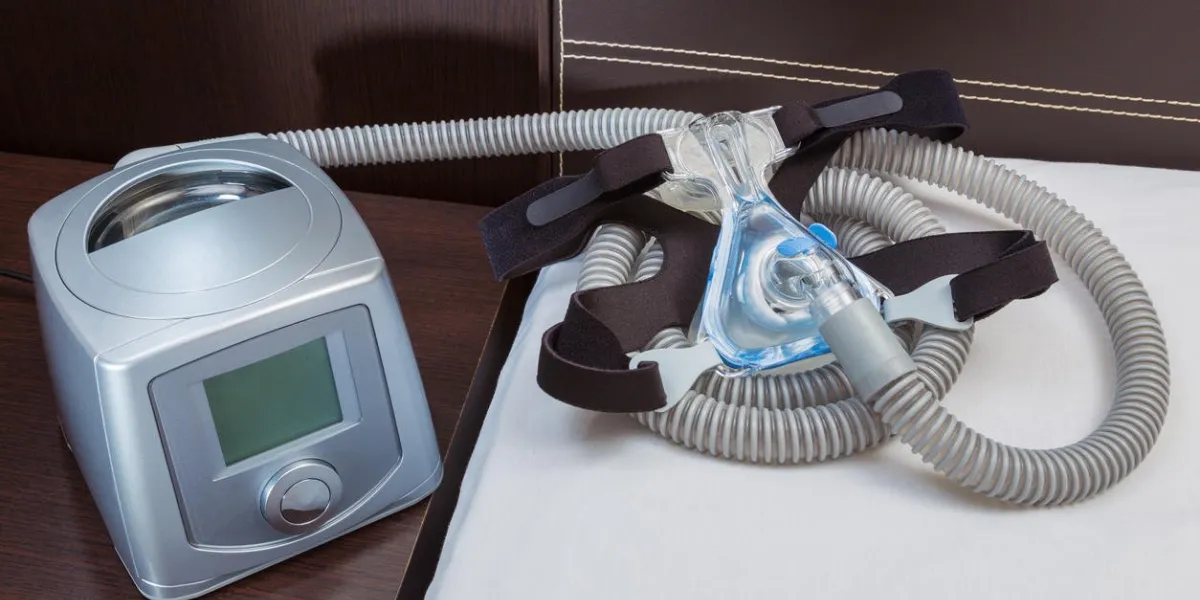 machine à cpap avec un tuyau d'air et un masque à engrenages dans une chambre