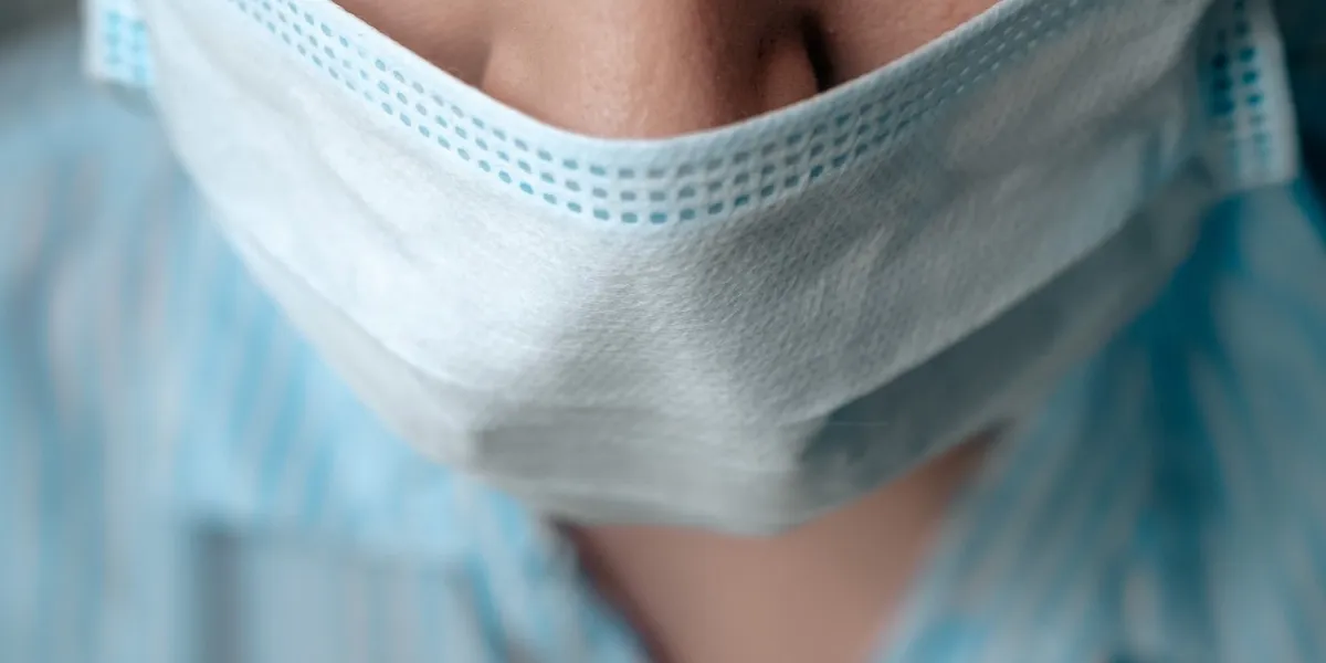 girl surgeon doctor puts surgical mask on her face preparation for surgery, infection protection, quarantine, epidemic, medicine, virus, flu concept close-up top view shot