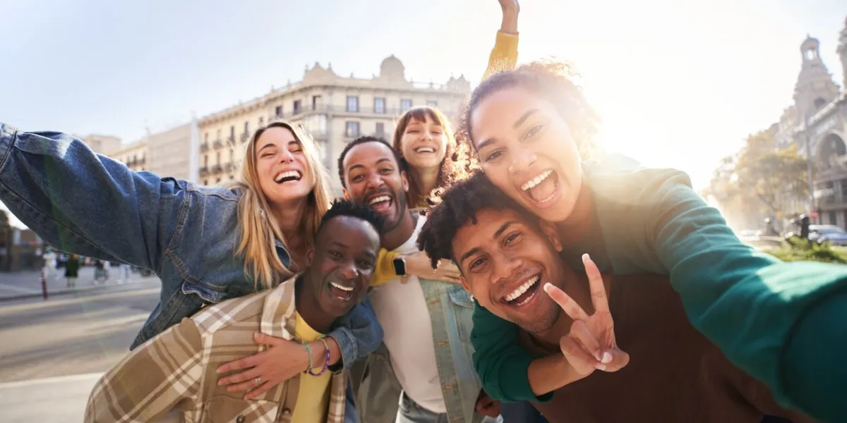 a group of cheerful students college friends having fun together as they travel through european cities happy community of diverse people selective focus on the smily couple taking the selfie