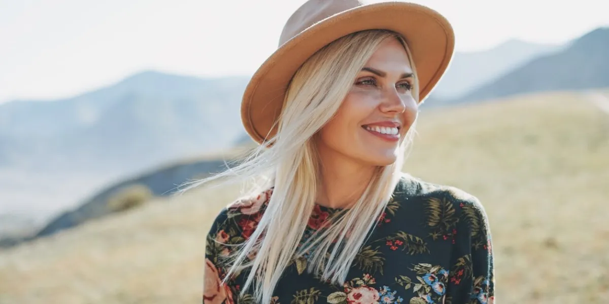 beautiful smiling blone young woman traveler in dress and felt hat on road, trip to the mountains, altai